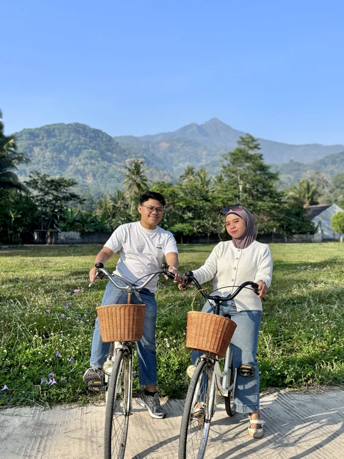 Bersepeda bersama dengan latar sawah dan pegunungan