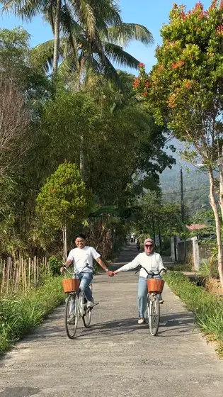 Bersepeda sambil bergandengan tangan di jalan desa